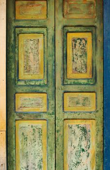 Old wooden door with fading green and yellow painting