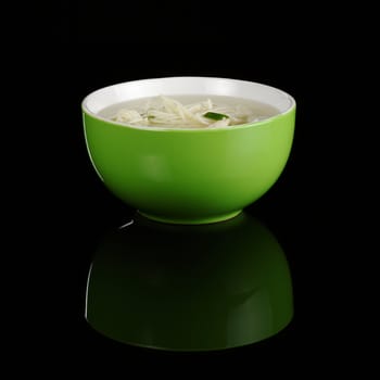 Chinese noodle soup in a green bowl photographed on black with a reflection 