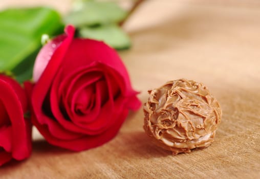 Truffle with red rose on wooden board (Very Shallow Depth of Field, Focus on the front of the truffle)