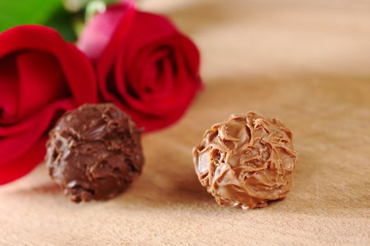 Truffles with red roses on wooden board (Very Shallow Depth of Field, Focus on the front of the right truffle)