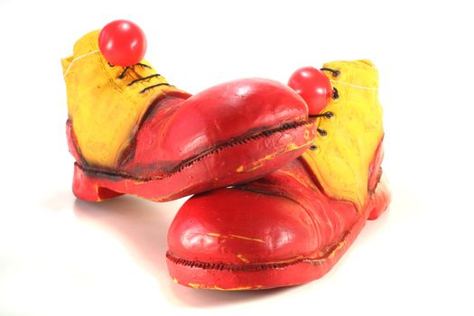red and yellow clown shoes with red clown noses on white background