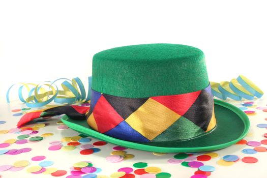 Carnival hat with colorful confetti and streamers on white background