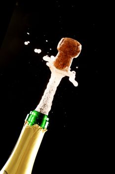Champagne cork bursting out of a green and gold bottle