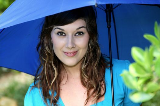 Beautiful smiling young brunette woman with a blue umbrella