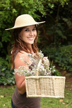 Gorgeous young lady doing gardening and holding a basket of cut flowers