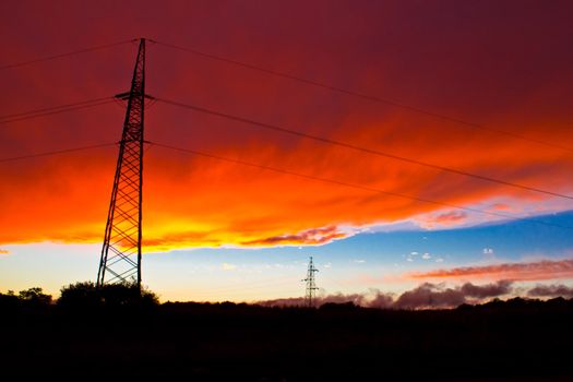 Armageddon sunset - red burning sky and long transmission power lines - lattice tower
