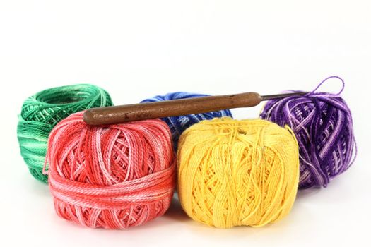colorful ball of wool and crochet hook on a white background