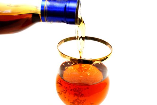 Zoomed bottleneck filling a glass with brown liquid