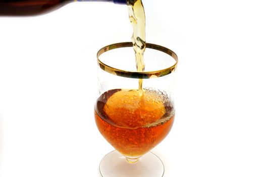 Brown bottle filling a glass with brown liquid