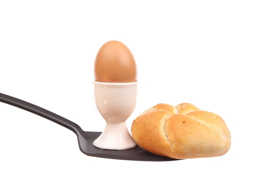 Egg and a bun on a spoon against a white background