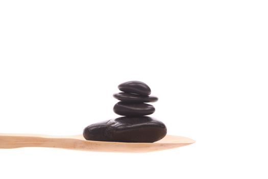 Massage-stone simply offered on a wooden spoon isolated on a white background 