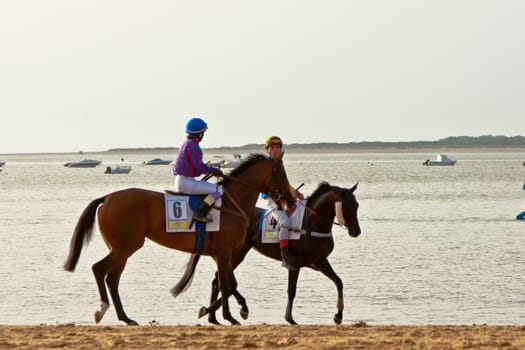 SANLUCAR DE BARRAMEDA, CADIZ, SPAIN - AUGUST 11: Unidentified riders at the start of race horses on Sanlucar de Barrameda beach on August 11, 2011 in Sanlucar de Barrameda, Cadiz, Spain.