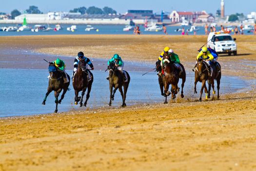 SANLUCAR DE BARRAMEDA, CADIZ, SPAIN - AUGUST 10: Unidentified riders race horses on Sanlucar de Barrameda beach on August 10, 2011 in Sanlucar de Barrameda, Cadiz, Spain.