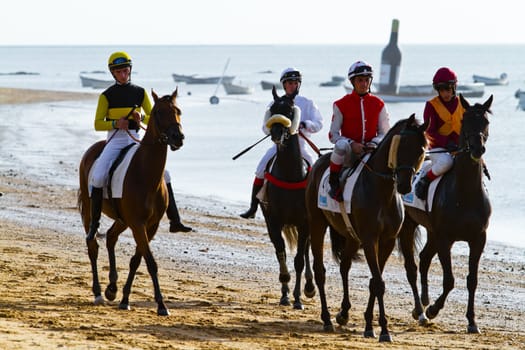 SANLUCAR DE BARRAMEDA, CADIZ, SPAIN - AUGUST 10: Unidentified riders at the start of race horses on Sanlucar de Barrameda beach on August 10, 2011 in Sanlucar de Barrameda, Cadiz, Spain.