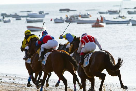 SANLUCAR DE BARRAMEDA, CADIZ, SPAIN - AUGUST 10: Unidentified riders race horses on Sanlucar de Barrameda beach on August 10, 2011 in Sanlucar de Barrameda, Cadiz, Spain.