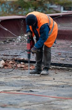 Workman Using Jackhammer on Roof of Building