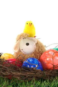 Easter basket with Easter eggs, sheep and chicks on a green meadow