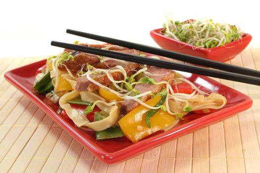 Duck breast with fried noodles, fresh vegetables and radish sprouts