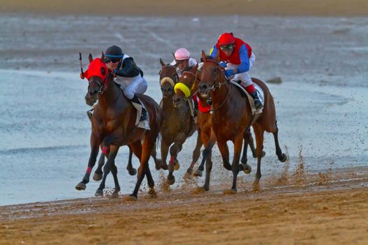 SANLUCAR DE BARRAMEDA, CADIZ, SPAIN - AUGUST 10: Unidentified riders race horses on Sanlucar de Barrameda beach on August 10, 2011 in Sanlucar de Barrameda, Cadiz, Spain.