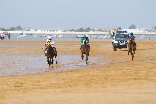 SANLUCAR DE BARRAMEDA, CADIZ, SPAIN - AUGUST 11: Unidentified riders race horses on Sanlucar de Barrameda beach on August 11, 2011 in Sanlucar de Barrameda, Cadiz, Spain.