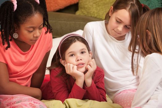 Sad little with hands on chin with friends at a sleepover