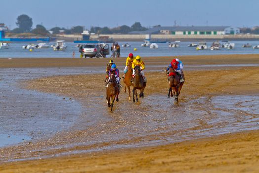 SANLUCAR DE BARRAMEDA, CADIZ, SPAIN - AUGUST 11: Unidentified riders race horses on Sanlucar de Barrameda beach on August 11, 2011 in Sanlucar de Barrameda, Cadiz, Spain.
