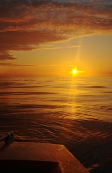 Sunset along the coast with the rear part of a boat and the tiller