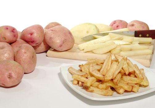 Freshly prepared French Fries on a Plate with Potatoes in the Background
