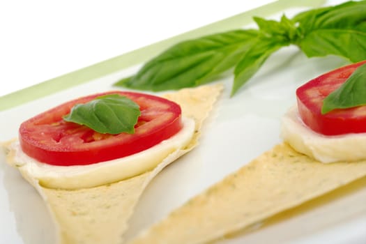 Appetizer: Mozzarella cheese, tomato slice and basil leaf on Crocantini (Selective Focus)