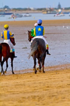 SANLUCAR DE BARRAMEDA, CADIZ, SPAIN - AUGUST 11: Unidentified riders at the start of race horses on Sanlucar de Barrameda beach on August 11, 2011 in Sanlucar de Barrameda, Cadiz, Spain.