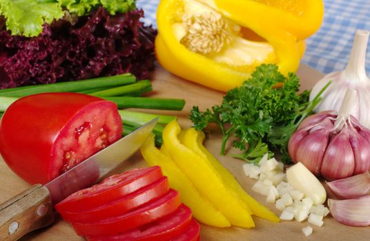 Cutting various vegetables for a salad on wooden board  