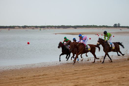 SANLUCAR DE BARRAMEDA, CADIZ, SPAIN - AUGUST 07: Unidentified riders race horses on Sanlucar de Barrameda beach on August 07, 2010 in Sanlucar de Barrameda, Cadiz, Spain.