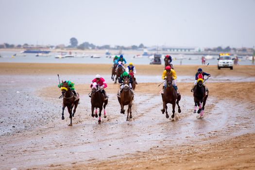 SANLUCAR DE BARRAMEDA, CADIZ, SPAIN - AUGUST 07: Unidentified riders race horses on Sanlucar de Barrameda beach on August 07, 2010 in Sanlucar de Barrameda, Cadiz, Spain.