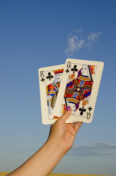 Hand holding pair of cards. King and queen cross.