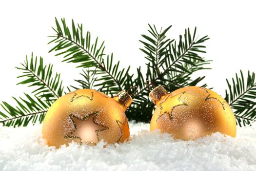 Golden Christmas balls and pine branches in the snow