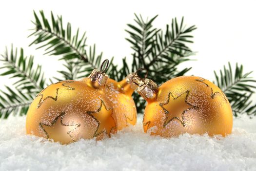 Golden Christmas balls and pine branches in the snow