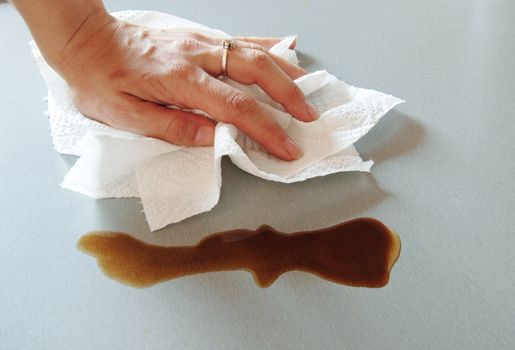 woman hand wiping spilled coffee with paper towel