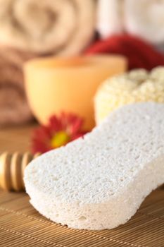 Spa still life with sponge and candle, towels in the back (Selective Focus, Focus on the front of the sponge)