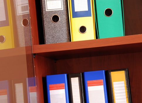 group of colorful files in office shelves indoors