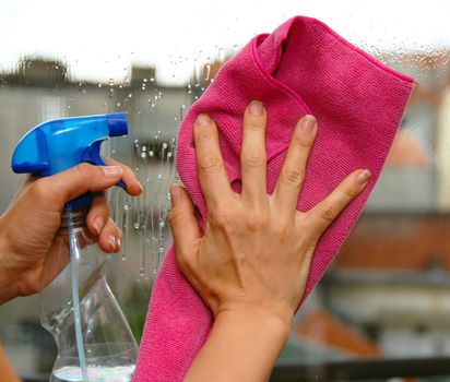young woman hands on window cleaning a glass