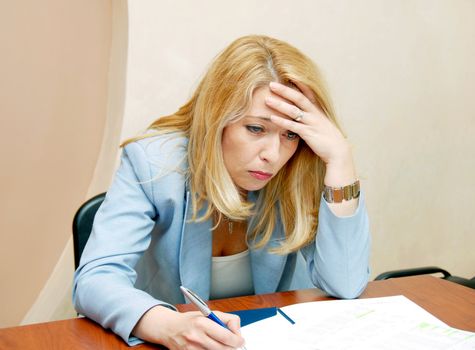 blond smiling stressed businesswoman hard working at the desk in office