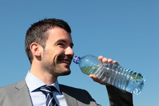 businessman drinking water with bottle in blue sky