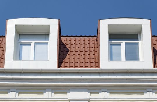 Two windows. A facade of a modern building with a tile roof