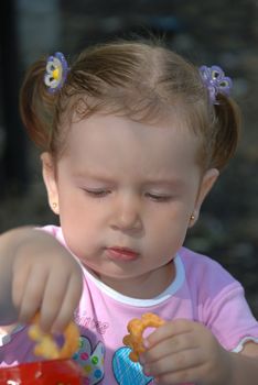 The girl taking cookie from a pack. Age - 2 years