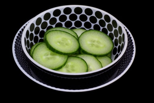 Isolated black/white bowl with cucumber slices.