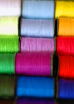 A close up photograph of multi-coloured spools of cotton.