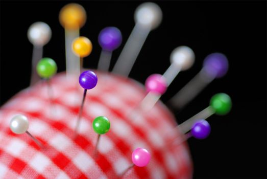 A red gingham pin cushion full of pins