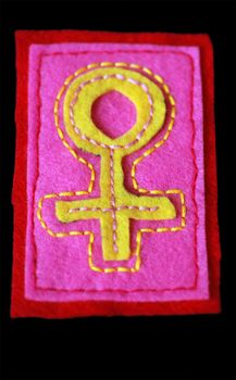 A hand-sewn venus symbol on felt with a black background