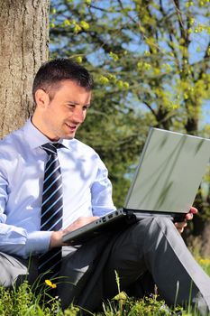 young businessman working with laptop in a park