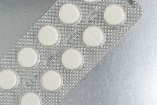 Macro of medical pills on a silver background.